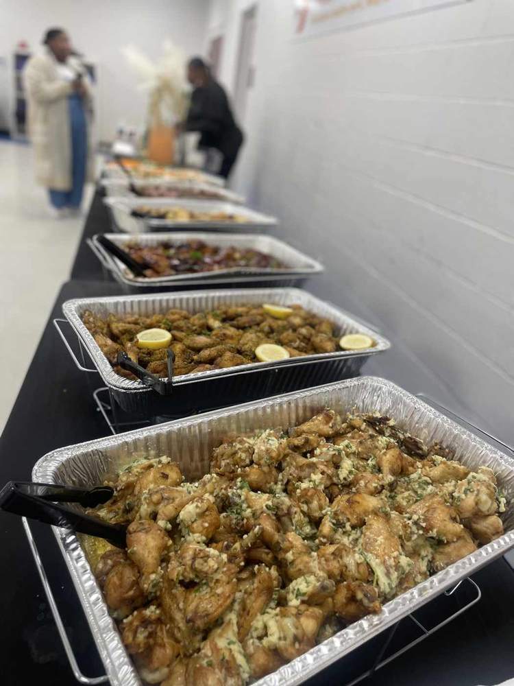 A long catered buffet with trays of seasoned wings