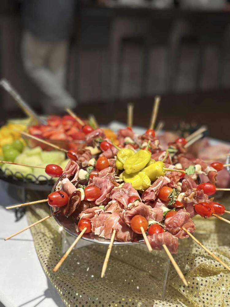 Charcuterie skewers arranged with tomatoes, cured meat and peppers