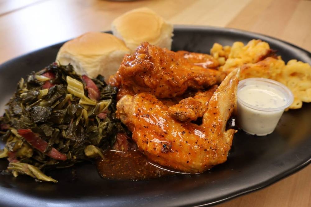 Glazed chicken served with greens, macaroni and cheese and dinner rolls