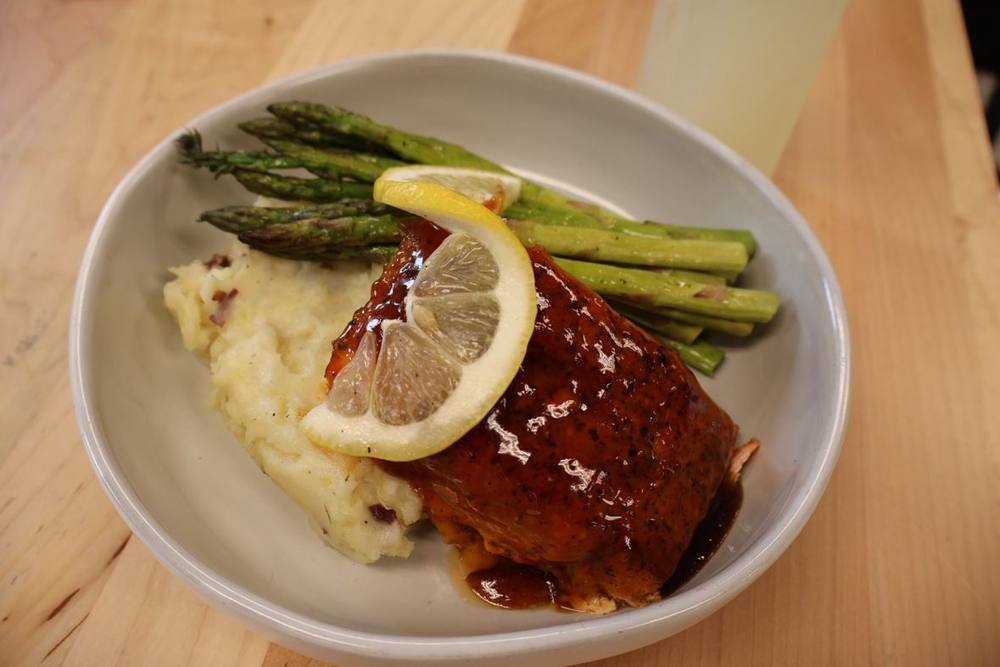 Glazed salmon served over mashed potatoes with roasted asparagus and lemon