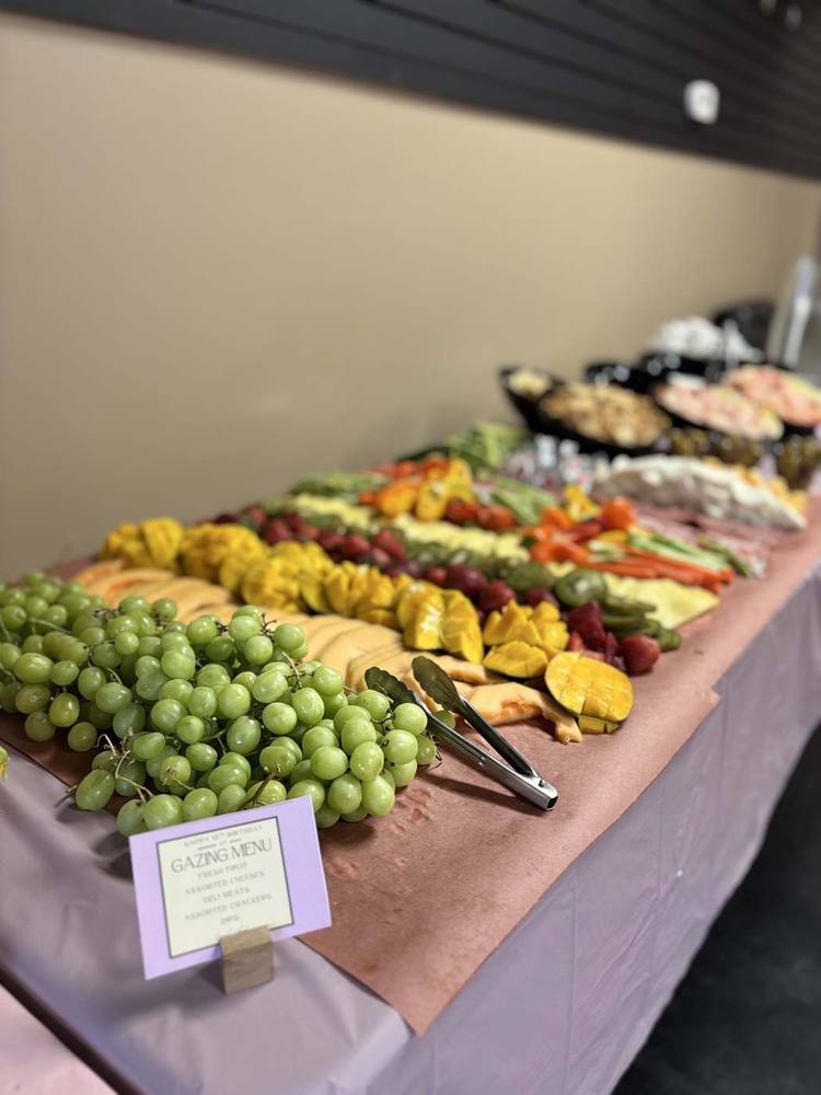 Long grazing table filled with fresh fruit, vegetables, cheese and charcuterie