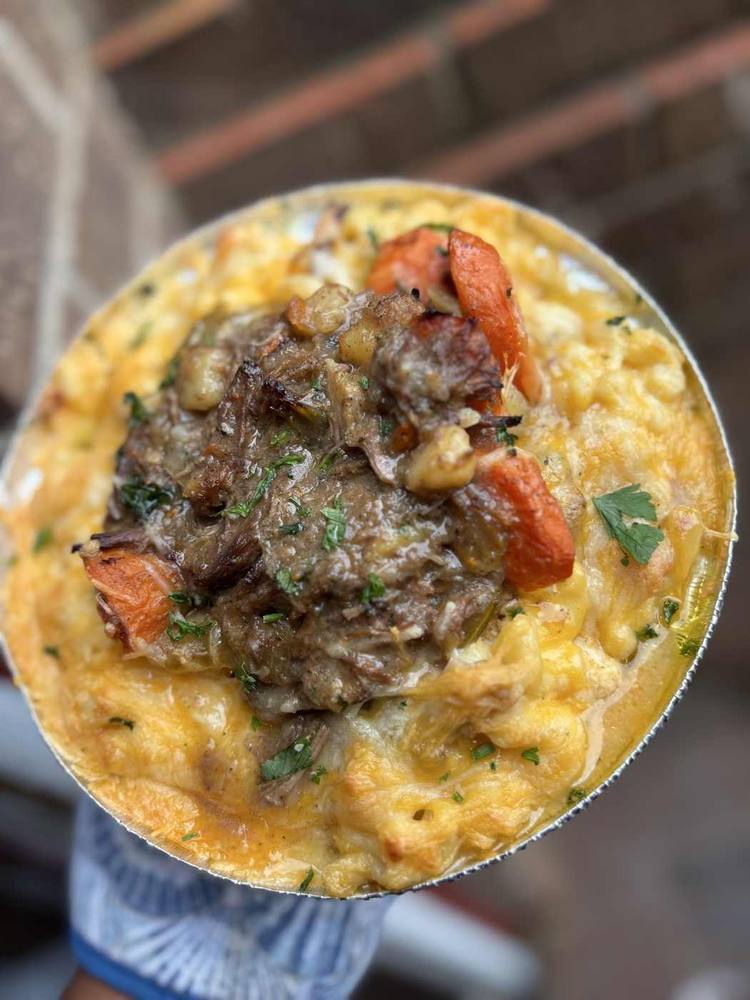 Creamy macaroni and cheese bowl topped with seasoned steak and peppers